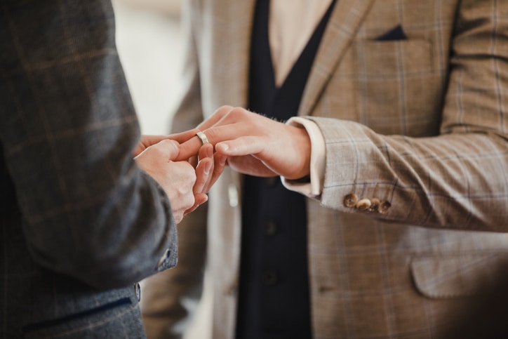 Two men are exchanging rings in a civil partnership