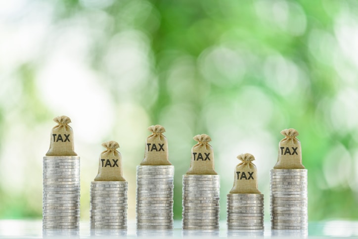 Tax collection, tax credit and benefit, financial concept : Tax bags rest atop coin stacks, depicting mandatory financial charge, type of levy imposed by a government on a taxpayer, individuals, etc.
