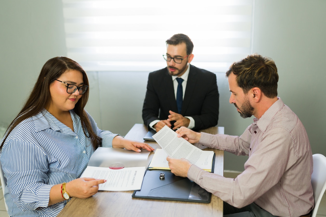 Serious couple having a meeting with an attorney, discussing and signing legal documents for a separation or divorce agreement