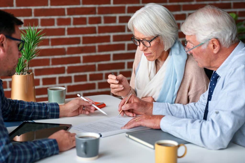 senior couple planning retirement signing contract for life insurance savings plan with financial advisor showing where to write signature